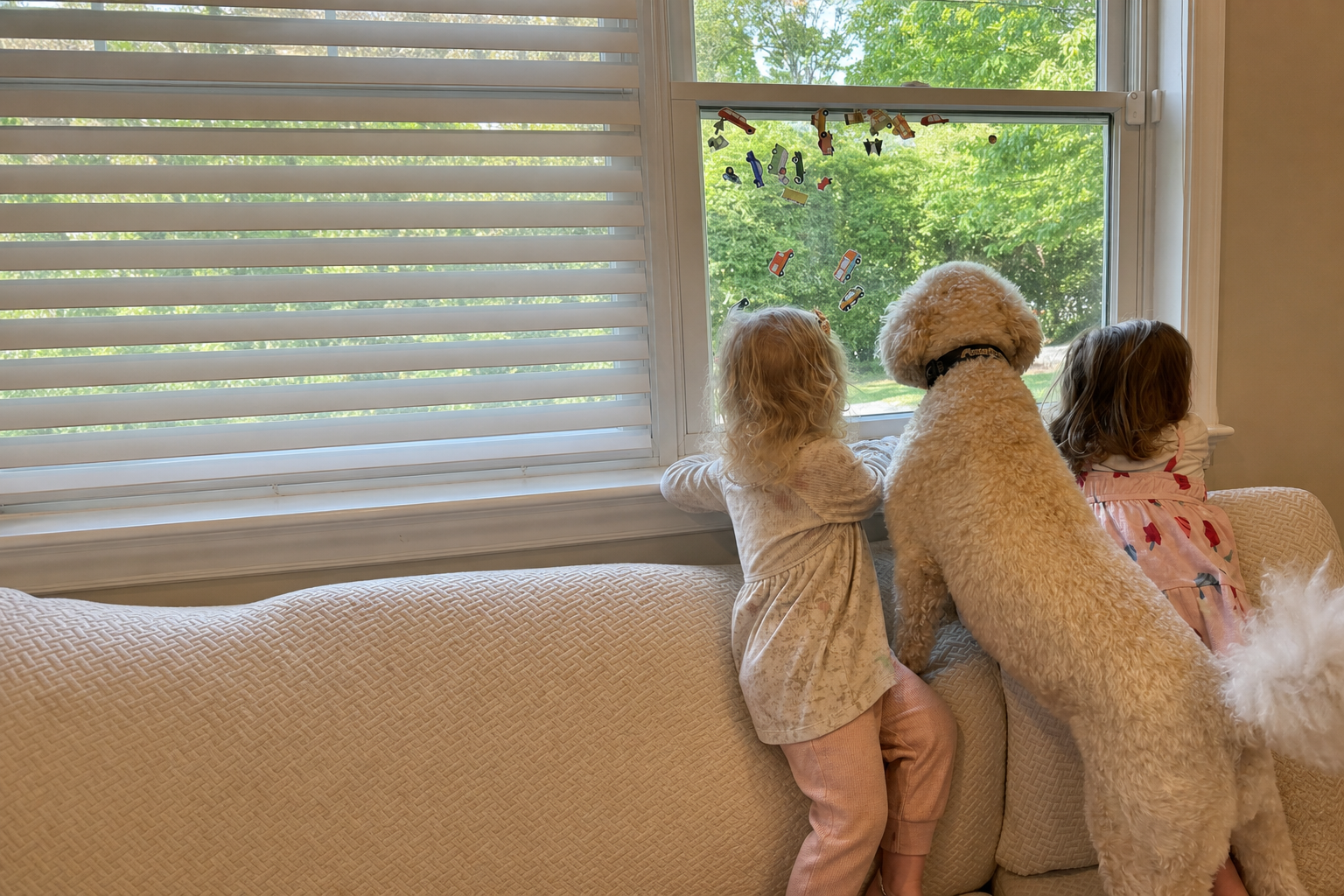 Twin girls and their family dog looking out the window
